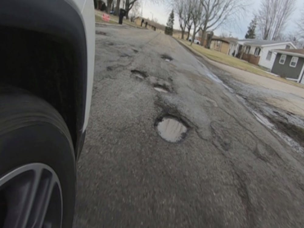 Potholes line W. Purdue Avenue between N. Lancaster Drive and N. Oakwood Avenue on Feb. 18, 2020.