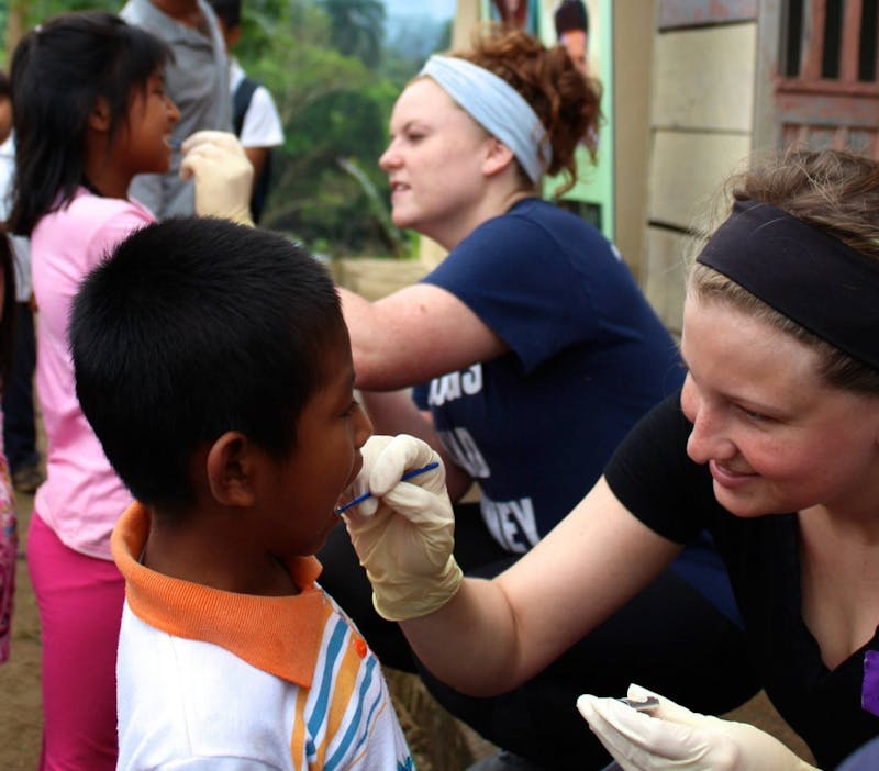 A member of Timmy Global Health cleans a child's teeth with fluoride in 2016 in Ecuador. Ball State's chapter of Timmy Global Health visited Ecuador to provide healthcare options to the community. Ella Penczek, Photo Provided.&nbsp;