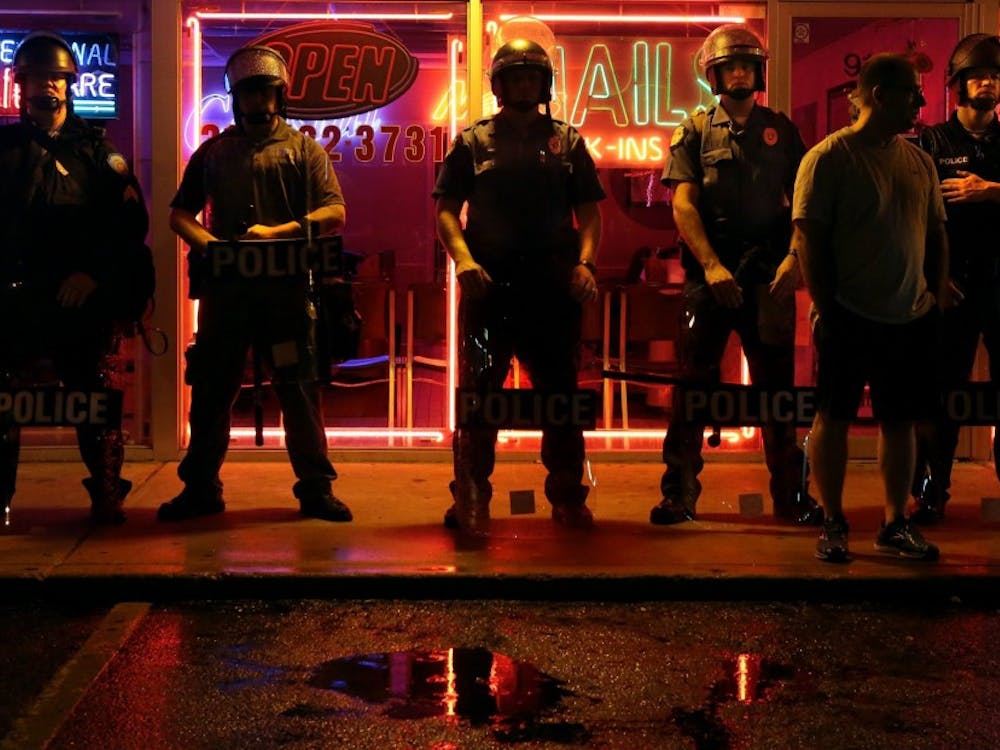 Police officers man their positions in front of Ferguson, Mo., businesses on West Florissant Avenue just after 10 p.m. on Saturday, Aug. 16, 2014. A curfew went into effect at midnight. (Robert Cohen/St. Louis Post-Dispatch/MCT)