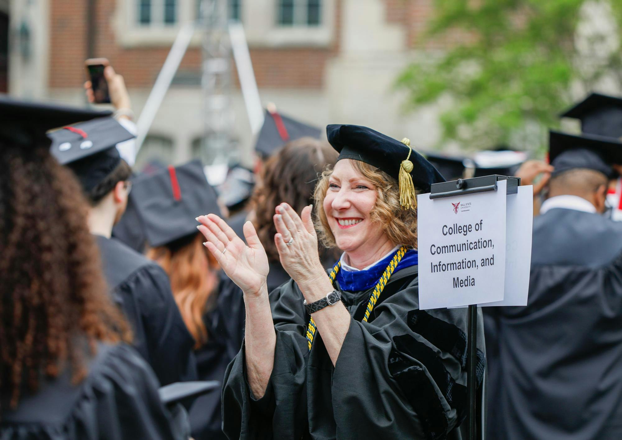 Dean of communications and media Paaige Turner claps as students stand celebrate graduation May 4 at The Quad. In her role Turner is responsible for 40-plus organizations founded and operated by and for students. Andrew Berger, DN