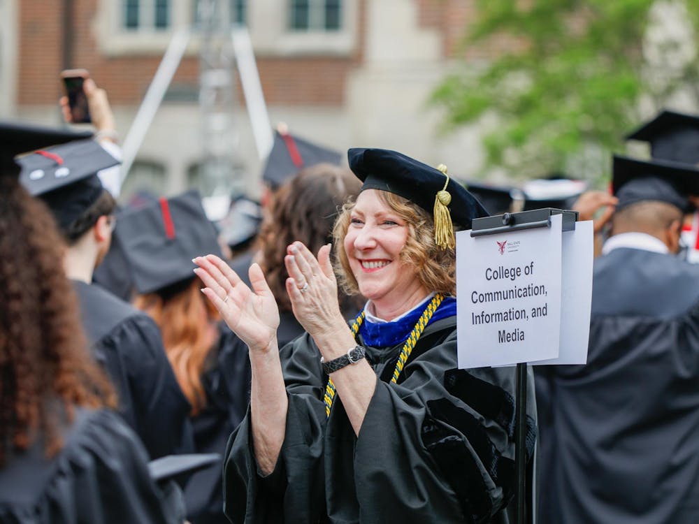 Dean of communications and media Paaige Turner claps as students stand celebrate graduation May 4 at The Quad. In her role Turner is responsible for 40-plus organizations founded and operated by and for students. Andrew Berger, DN