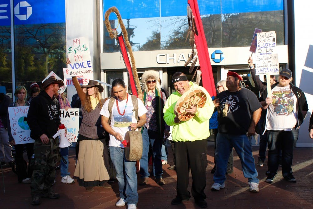 <p>Dakota Access Pipeline protesters stand outside the Chase building in downtown Indianapolis on Nov. 15 to encourage others to divest from the companies like Chase Bank that are funding the construction of the pipeline. Protesters are also encouraged to send donations to the Standing Rock Sioux Tribe and to their legal defense fund. <em>Kelli Huth // Photo Provided</em></p>