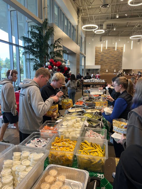 Students assemble their walking tacos with various toppings such as lettuce, tomato, black olives, dill pickles and choices for dressings or sour cream Oct. 15 at North Dining. Ellie Marker, DN