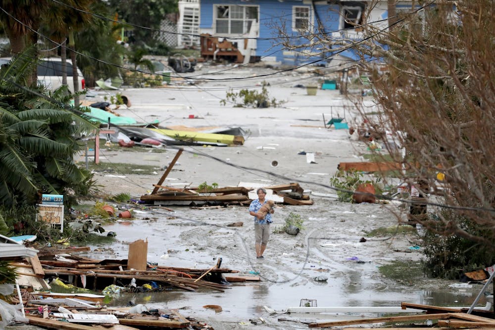Pat Ton, holding his dog Ginger, takes in the damage to homes and businesses on 3rd Street at Fort Myers Beach on Thursday, Sep. 29, 2022, which was mostly destroyed after Hurricane Ian made landfall overnight on Wednesday. (Douglas R. Clifford/Tamps Bay Times/TNS)