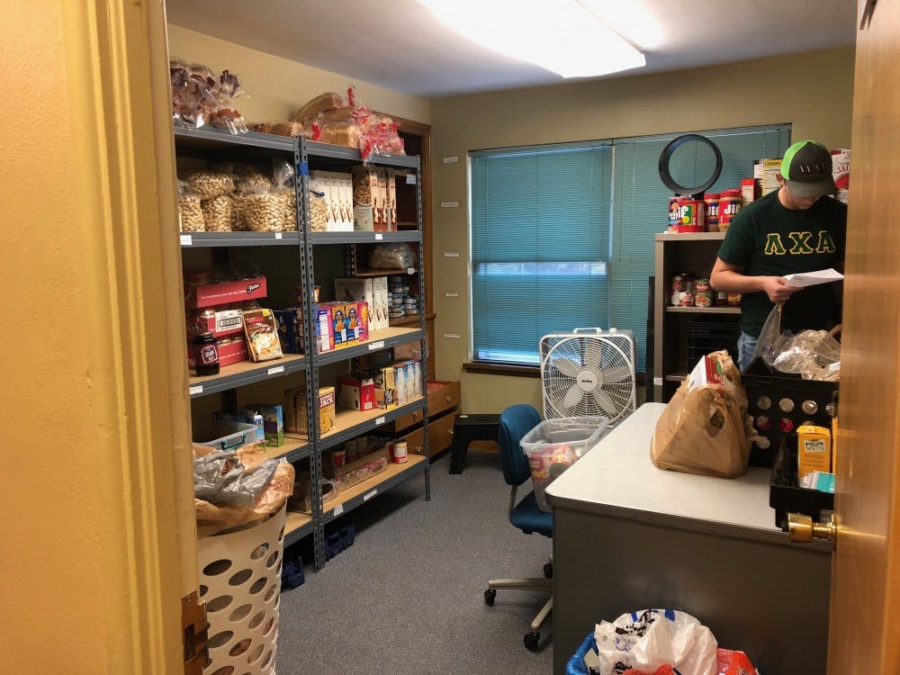 <p>Trevor Millspaugh gathers food for a client in Cardinal Kitchen's nine-by-12 foot stockroom in the Multicultural Center. Cardinal Kitchen is currently crowdfunding to relocate to a different space. <strong>Sara Barker, DN</strong></p>