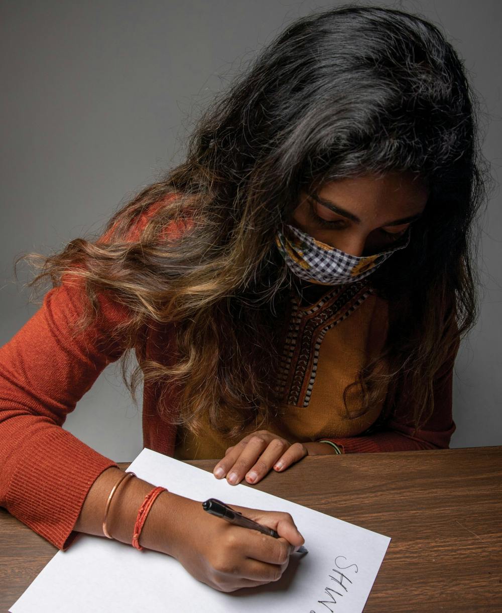 Shwetha Sundarrajan writes down misspellings of her name Nov. 3, 2020, in the photojournalism studio. Throughout Sundarrajan’s life, her name has been misspelled and misspoken. Jacob Musselman, DN Illustration