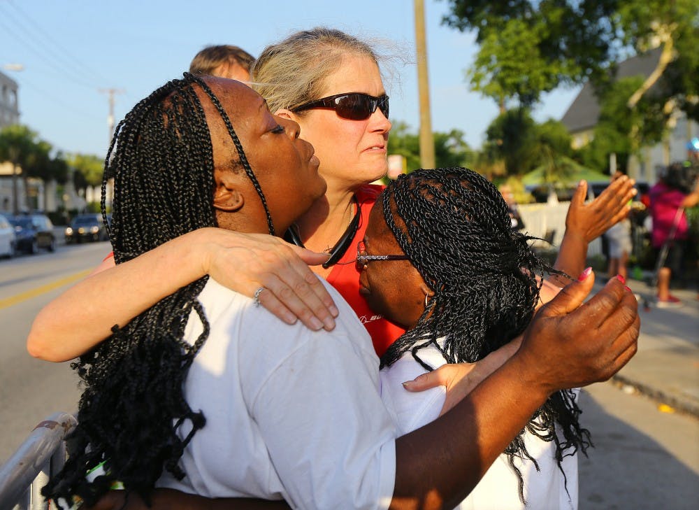 Crissa Jackson, from left, Cynthia Coates and Cynthia Jackson embrace one another and pray as they wait in line for the doors to reopen to the "Mother" Emanuel A.M.E. Church on Sunday, June 21, 2015, in Charleston, S.C. (Curtis Compton/Atlanta Journal-Constitution/TNS)