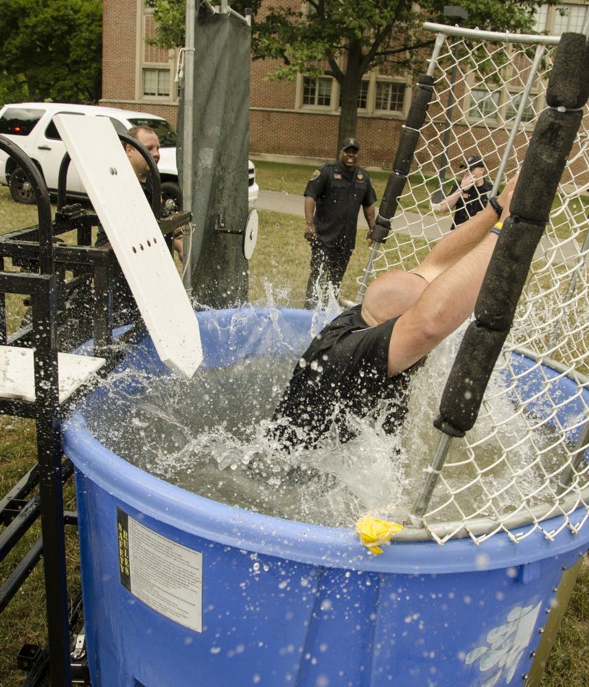 University Police Department Officer Eric Reffitt takes a dive after bystanders hit the mark of the dunk tank. Students can dunk-a-cop from 10 a.m. to 2 p.m. on August  at the Scramble Light. DN FILE PHOTO COREY OHLENKAMP