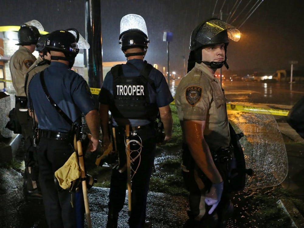 Missouri Highway Patrol officers and St. Louis County police stand in the rain on Saturday next to the McDonald