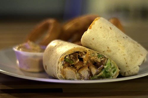 A fresh buffalo wrap with ranch dressing and onion fries sits on the far end of a packed bar at Savages, a bar in downtown Muncie. DN PHOTO RJ RICKER
