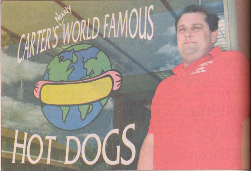 This image from 1998 shows Mark Carter, owner and operator of Carter's Nearly World Famous Hot Dogs, standing in front of his store in the Village. Carter's store used to be located where Jimmy John's sits today. Digital Media Repository, Photo Courtesy