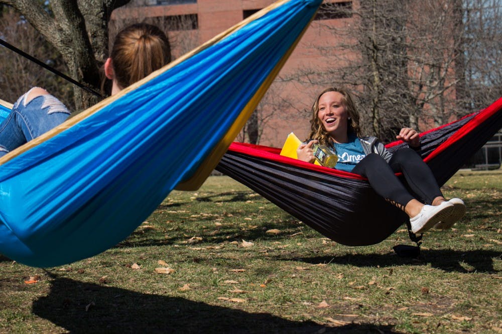 <p>Ashley Miller and Lauren Hamil share a laugh after setting up their hammocks to enjoy the weather Feb. 27. <strong>Eric Pritchett, DN</strong></p>