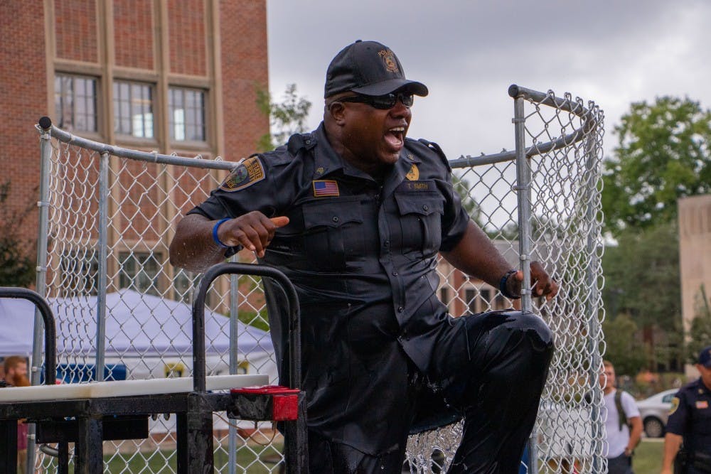 <p>Lieutenant Terrell Smith climbs out of the water tub after being dunked next to the Scramble Light on Aug. 22, 2019. Students could buy two automatic dunks for $10. <strong>Jacob Musselman, DN</strong></p>