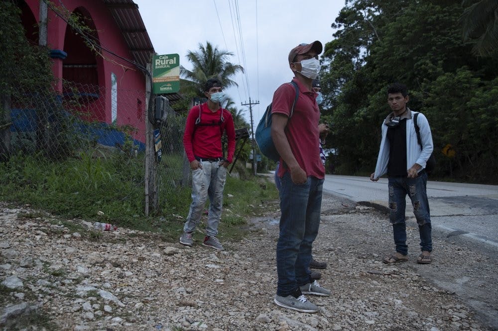 Honduras migrant Olvin Suazo, center, accompanied by others hitch a ride in San Luis Peten, Guatemala, Saturday, Oct. 3, 2020. Early Saturday, hundreds of migrants who had entered Guatemala this week without registering were being bused back to their country's border by authorities after running into a large roadblock. (AP Photo/Moises Castillo)