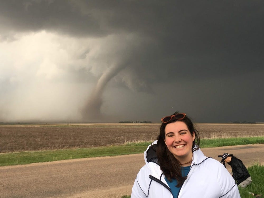 <p>Liz Szewczyk, senior meteorology major, poses for a photo in front of a tornado in McCook, Nebraska. Szewczyk chased storms over summer break, seeing five tornados on her first day. <strong>Liz Szewczyk, photo provided.&nbsp;</strong></p>