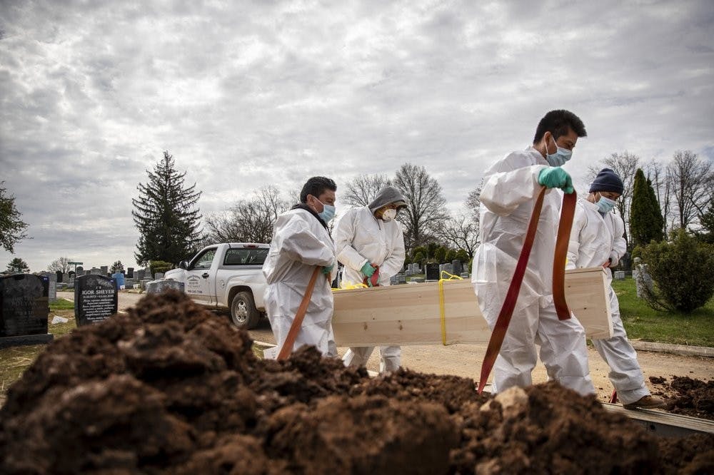 Gravediggers carry the casket of someone presumed to have died from coronavirus as they are buried without any family present April 7, 2020, at Mount Richmond Cemetery in the Staten Island borough of New York. In a marathon of grief at this small Jewish cemetery mounds of dirt are piling up as graves are opened, vans are constantly arriving with bodies aboard and a line of white signs is being pressed into the ground marking plots soon to be occupied. (AP Photo/David Goldman)