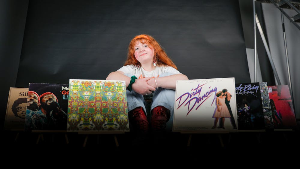 Third-year journalism major Meghan Braddy poses with some of her favorite records Feb. 24 in the Arts and Journalism Building. Braddy sees listening to her records as therapy. Andrew Berger, DN