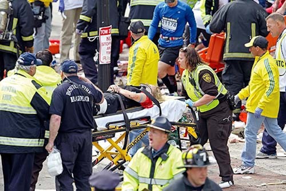 Web photo - Emergency personnel assist the victims at the scene of a bomb blast during the Boston Marathon today. At the time of publication, three people have been announced dead from the explosions. MCT PHOTO