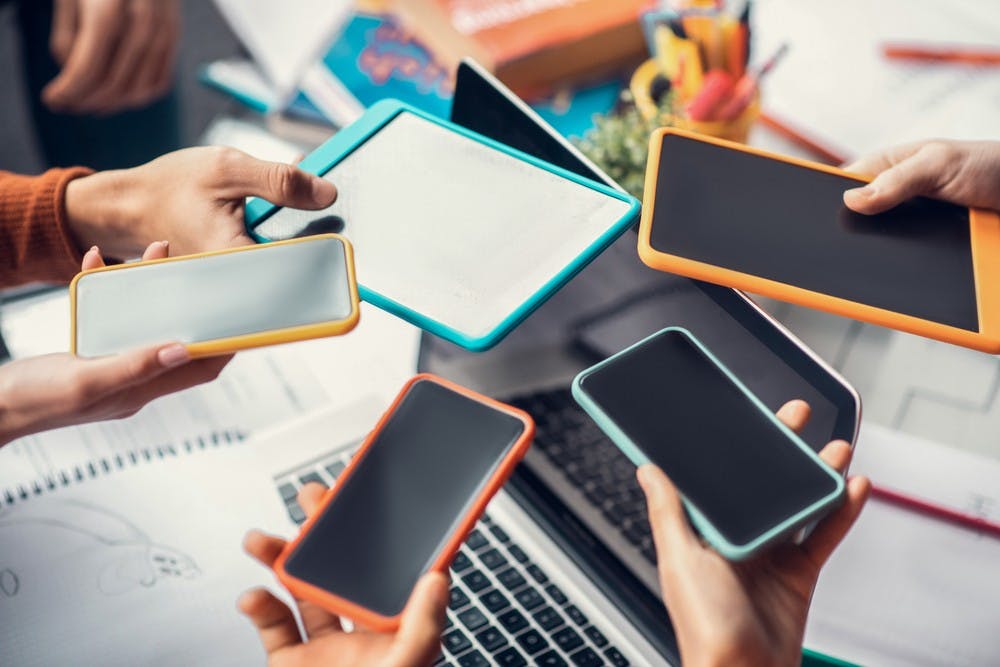 Close up of students holding their phones and tablets while using gadgets for study