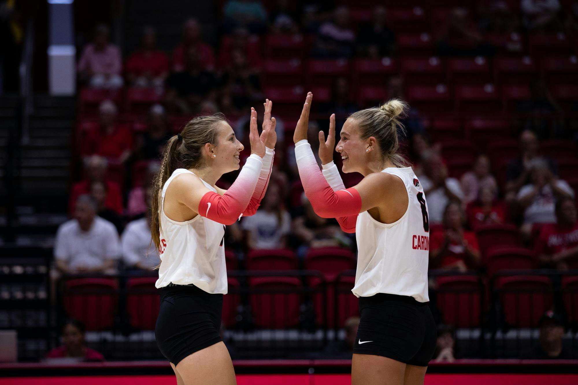 Graduate student outside hitter Noelle VanOort (left) and junior setter Lindsey Green (right) high-five during a game against Cedarville University Aug. 23 at Worthen Arena. The Cardinals won 3-2. Meghan Sawitzke, DN