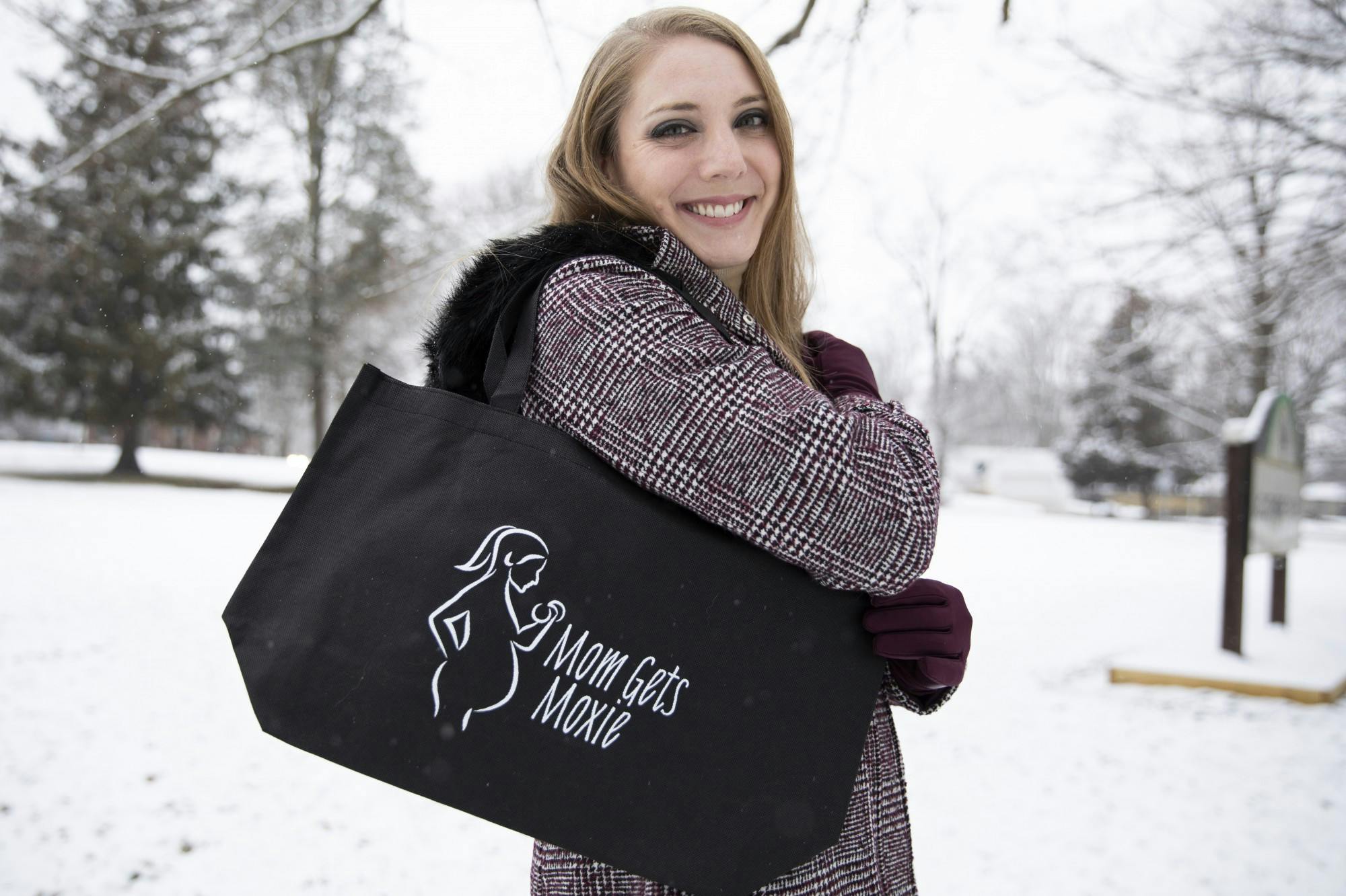 Brittany Scott poses for a portrait with her Mom Gets Moxie tote bag Jan. 16, 2021, at Guthrie Park. On her Mom Gets Moxie Instagram page, Scott posts free workouts for pregnant and postpartum people to do from the comfort of their homes with the equipment they have, such as dumbbells, yoga mats, resistance bands and towels. Jacob Musselman, DN