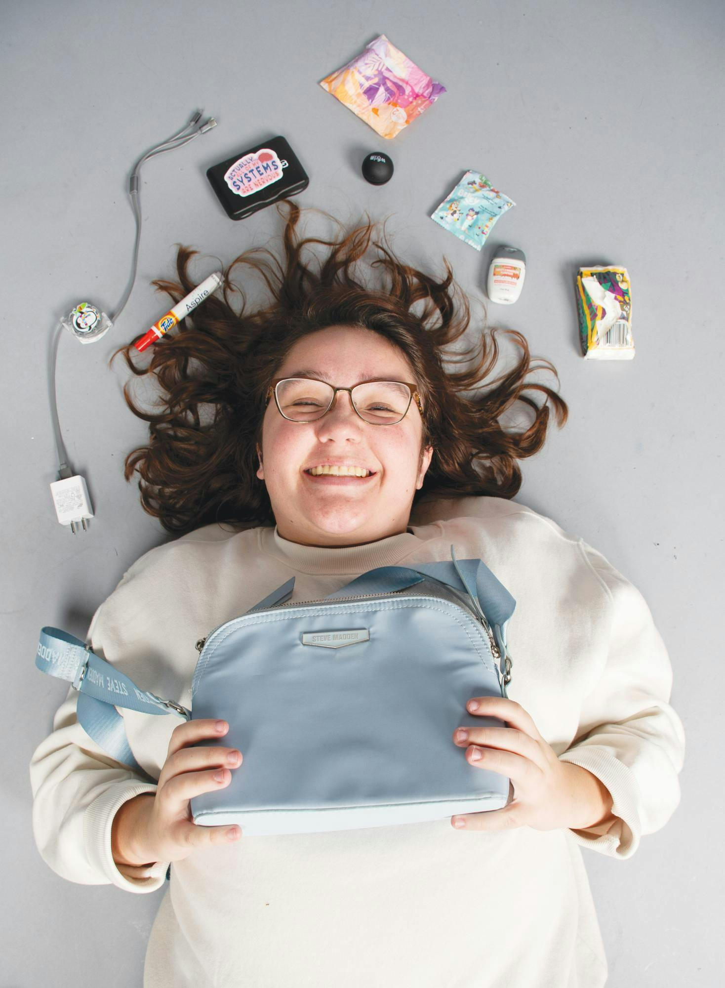 Shelby Anderson poses by laying on the floor with her bag and the items surrounding her head Nov. 6 in Muncie, Ind. Kadin Bright, DN