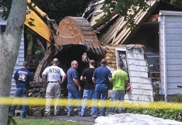 A backhoe is used to remove large debris from the area surrounding Charter Oak Avenue in East Haven, Connecticut, on Saturday, August 9, 2013, following Friday morning&apos;s plane crash. (Brad Horrigan/Hartford Courant/MCT)