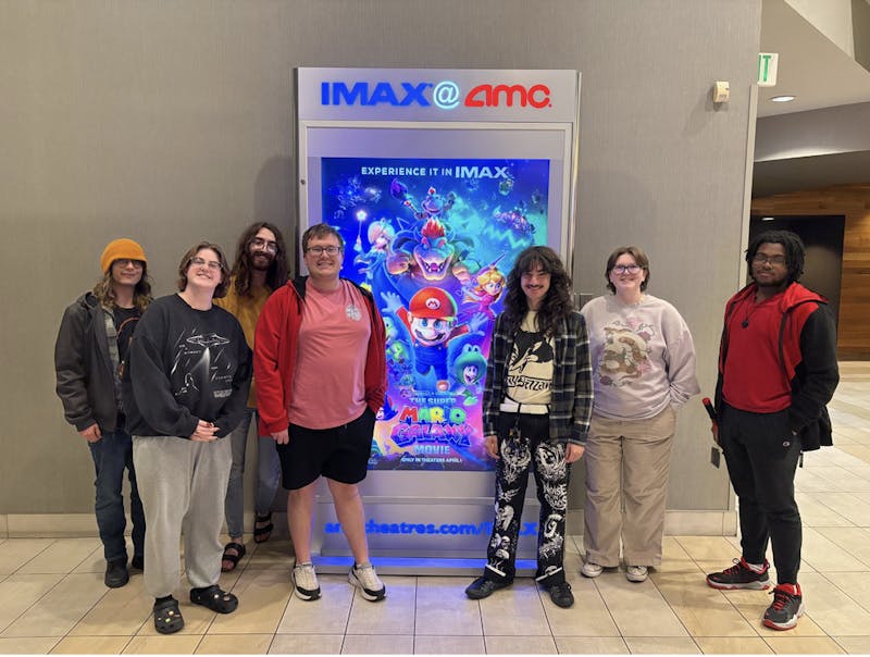From left to right, Byte members Vinnie LeBeau, Sam Jasionowski, Ian Frasier, Mason Mundy, Chris Dawson, Willow Emig, and Jax Lomax standing next to a poster for 'The Super Mario Galaxy Movie' inside of a movie theater.