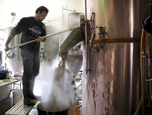 Eaton rakes spent grains from what’s called the “lauter tun,” which is the where sugars are extracted from the grains. A local farmer picks up the used grains to feed to livestock. PHOTO PROVIDED BY TYLER STEWART