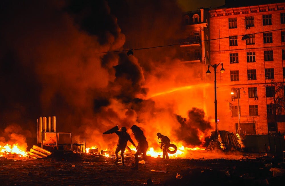 Activists in Kiev, Ukraine, run to the front lines of a protest while holding shields and throwing stones Jan. 22. Ukraine special forces tossed grenades at protesters who continued despite the attack. PHOTO PROVIDED BY ILYA VARLAMOV