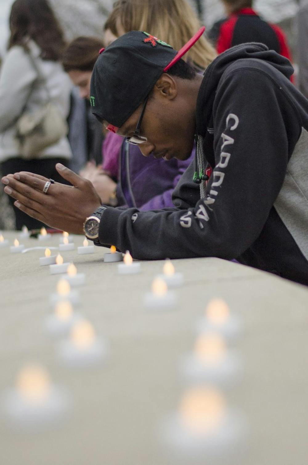 Daishawn Smith, a junior social work major, kneels at Frog Baby to pray on Nov. 16 at the prayer vigil. Those in attendance paid respects to whose lives were lost in Paris, Baghdad and Beirut this weekend. DN PHOTO BREANNA DAUGHERTY