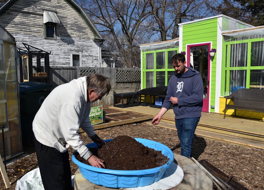 Brian Carless (Right) rolls up his sleeves to join Jeff Brubaker (Left) mix the soil for Sparky's Corner Greenhouse on Feb. 24 in Muncie, Ind. Ella Howell, DN