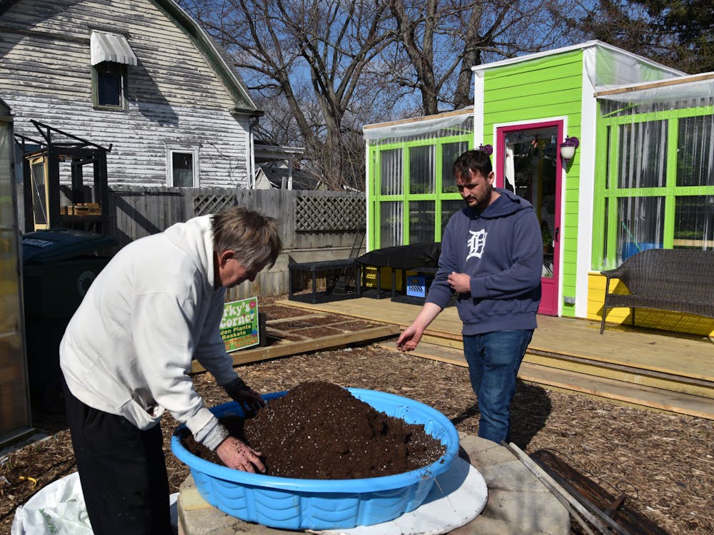 Brian Carless (Right) rolls up his sleeves to join Jeff Brubaker (Left) mix the soil for Sparky's Corner Greenhouse on Feb. 24 in Muncie, Ind. Ella Howell, DN