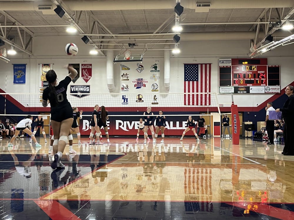 Junior setter Emma Jennings prepares to serve the ball to the Lady Vikings. The serve led to the match point that won the set for Muncie Central. PHOTO BY EVAN SHOTTS.