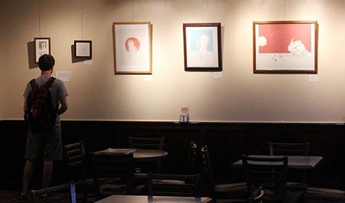 A student looks at the featured artwork displayed on the walls of the Cup.  The Glue and Scissors Society event showcased community produced art entries that will remain at the Cup for the remainder of the month. DN PHOTO KRYSTAL BYERS 