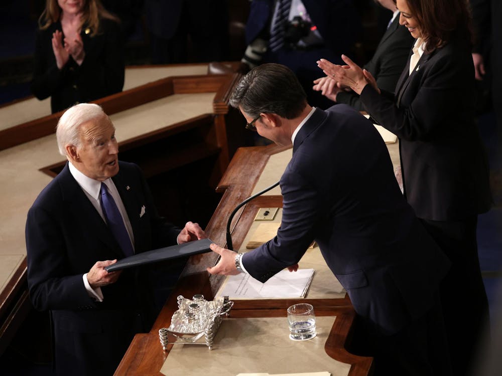 WASHINGTON, DC - MARCH 07: U.S. President Joe Biden gives a copy of his speech to Speaker of the House Mike Johnson (R-LA) as Vice President Kamala Harris applauds as he arrives for the State of the Union address in the House chamber at the U.S. Capitol on March 07, 2024 in Washington, DC. This is Biden’s last State of the Union address before the general election this coming November. (Photo by Alex Wong/Getty Images)