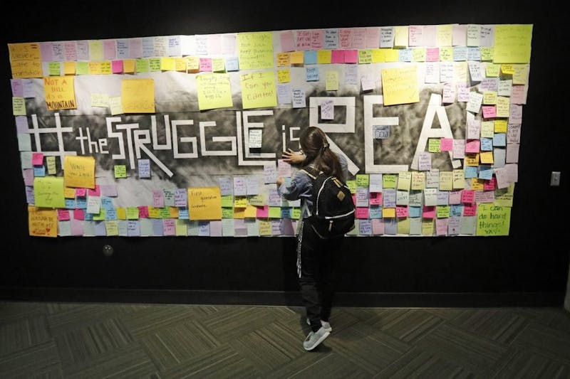 In this Nov. 14, 2019, photo, a student attaches a note to the Resilience Project board on the campus of Utah Valley University, in Orem, Utah. The purpose of the project is to let students know that it is OK to struggle. More college students are turning to their schools for help with anxiety, depression and other mental health problems. That's according to an Associated Press review of more than three dozen public universities. (AP Photo/Rick Bowmer)