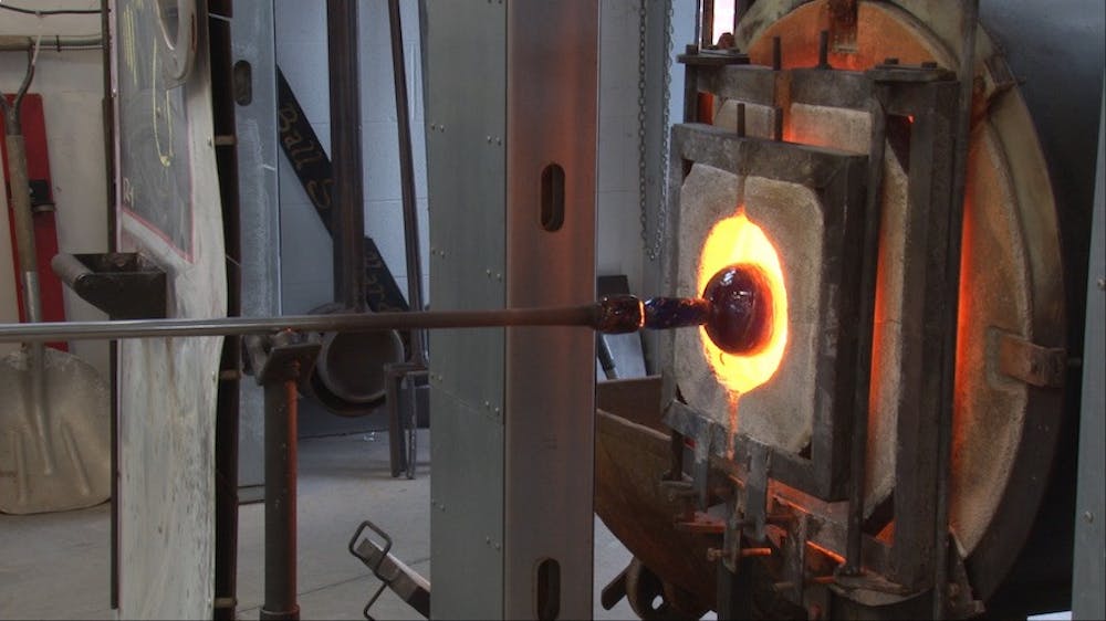 <p>Evan Burnette heats a glass pot at the Glick Center for Glass. <em>PHOTO BY MICHAEL KUHN</em></p>