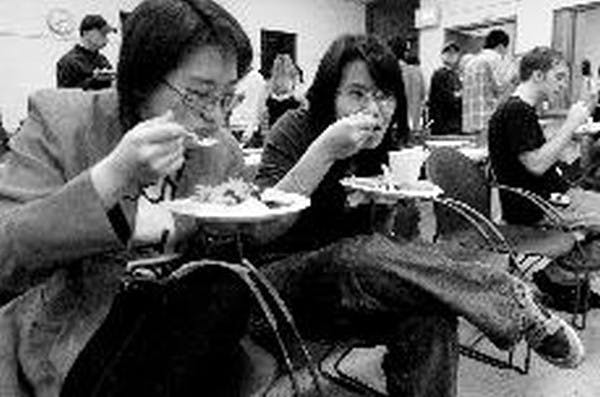 Shyr-Herng Yuh and Erida Kho indulge in a plate of Chinese food Sunday night during a Chinese New Year celebration at the Shideler Apartments main office.  DN PHOTO/ JEFFREY FURTICELLA
