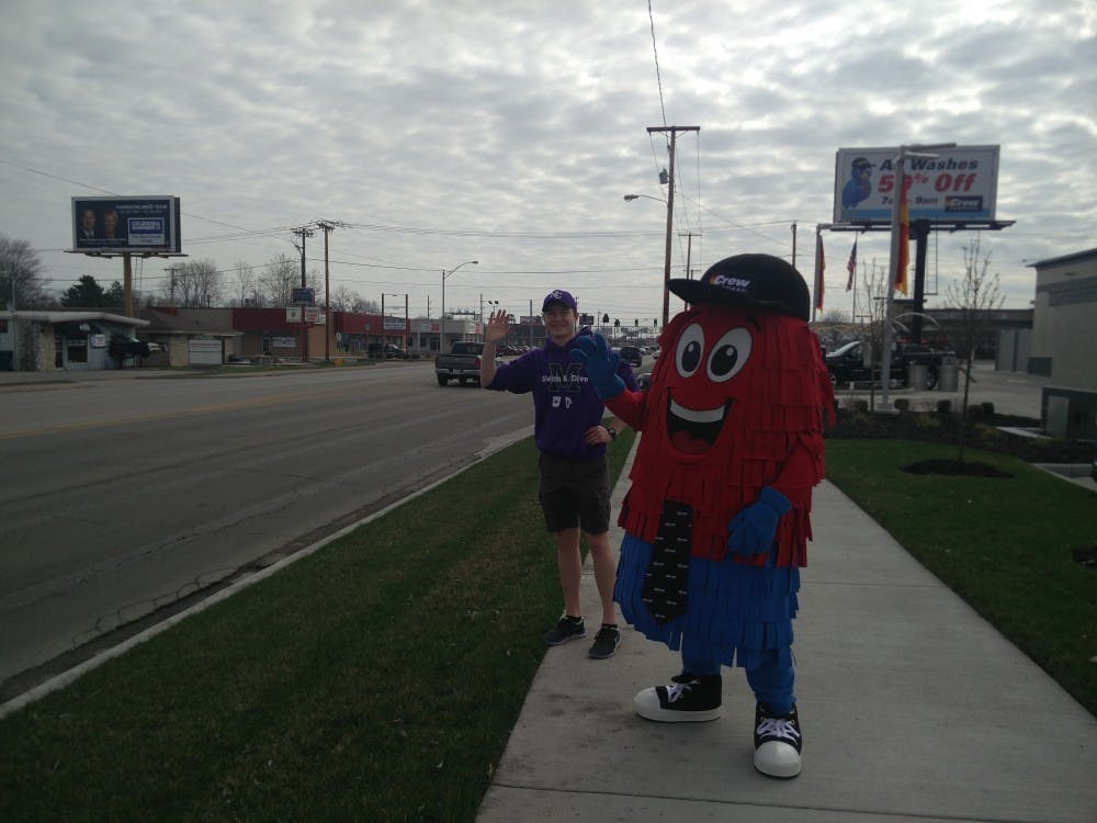 <p>Spinner, the mascot of Crew Carwash, and a volunteer from Muncie Community Schools (MCS) wave at passing vehicles April 6 by the side of McGalliard Road. Crew Carwash is hosting a fundraiser this weekend for MCS at the car wash's McGalliard Road location. <strong>Rohith Rao, DN</strong></p>