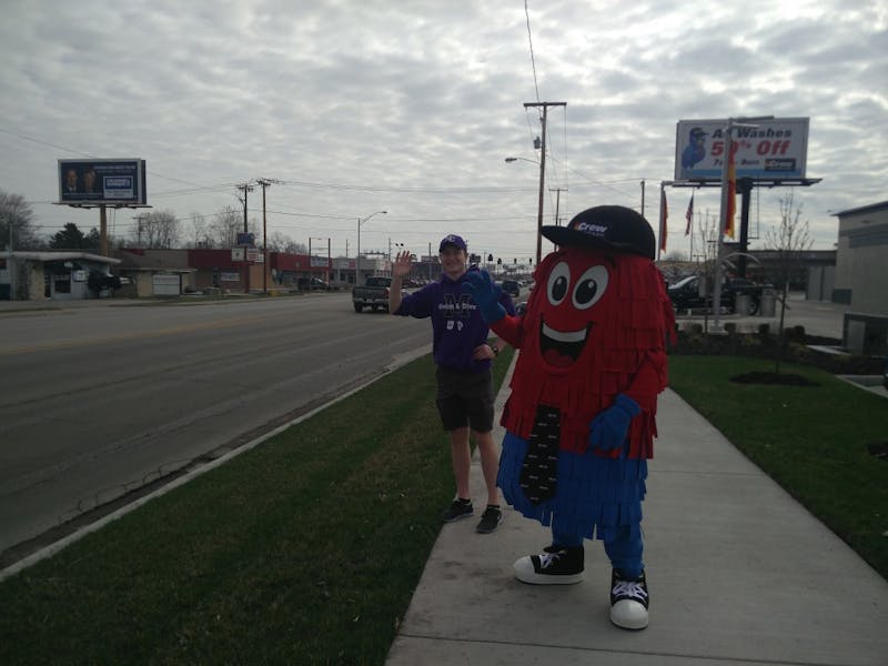 Spinner, the mascot of Crew Carwash, and a volunteer from Muncie Community Schools (MCS) wave at passing vehicles April 6 by the side of McGalliard Road. Crew Carwash is hosting a fundraiser this weekend for MCS at the car wash's McGalliard Road location. Rohith Rao, DN
