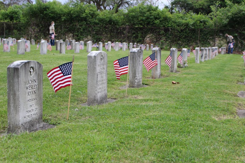 Boy Scouts and their families plant flags beside each headstone May 21, 2020, at Beech Grove Cemetery. Scouts in Muncie leave flags before Memorial Day in remembrance of fallen veterans. Jenna Gorsage, DN