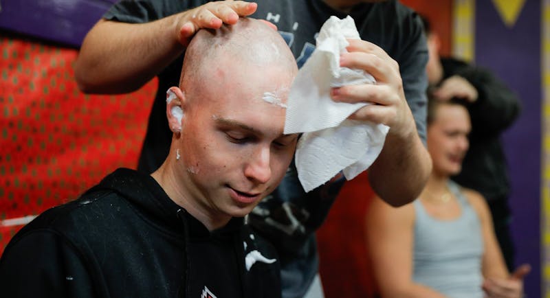 Ty Ransburg has his head wiped clean as his shave is finished Dec. 2 at the Ball State Sigma Alpha Epsilon house. Ransburg says he wants to stay positive and that the the support from his friends makes it much easier. Andrew Berger, DN