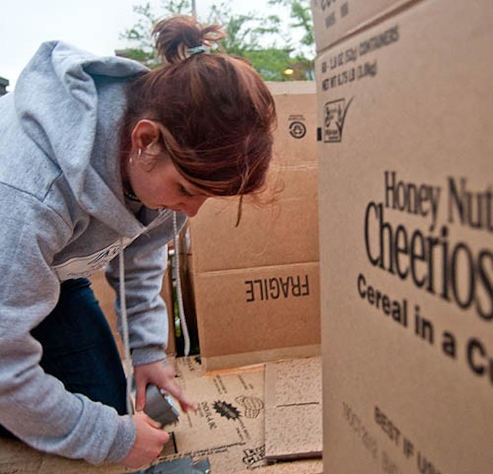 Sophomore Erin Cromer secures the boxes that make up the floor of her house as part of Box City held Friday in front of DeHority. Box City challenges students to spend one night in a cardboard box to bring awareness to the issue of homelessness. DN PHOTO JONATHAN MIKSANEK