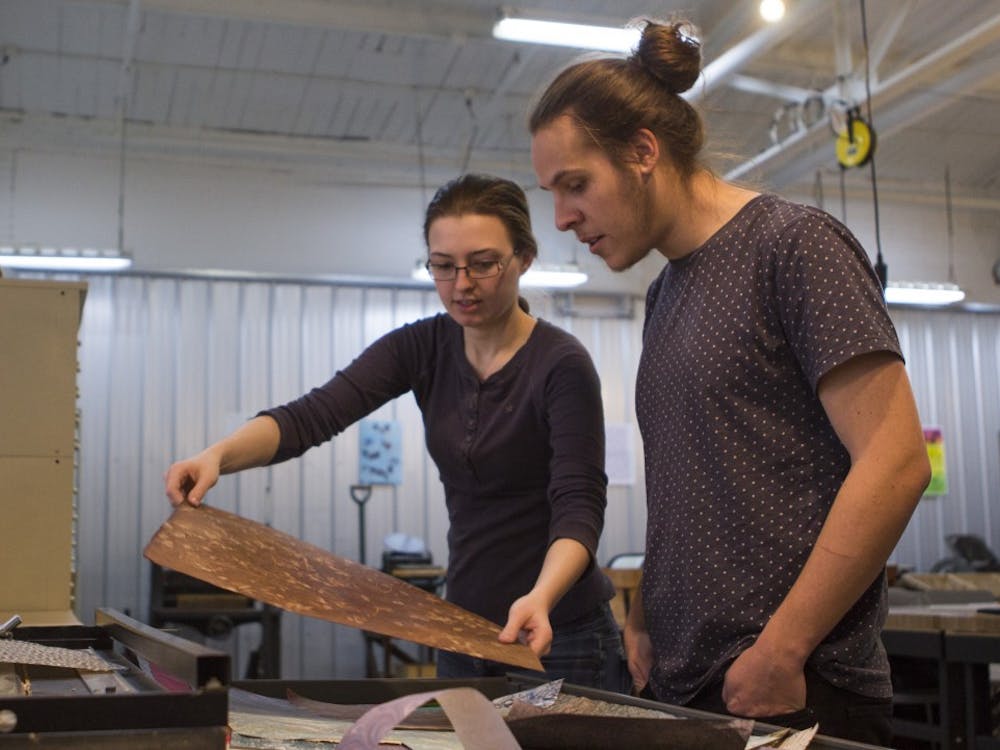 Graduate student J Collings and junior drawing major Kaitlyn Sims look through paper to choose for NAME'S book cover at the Book Arts Collaborative in downtown Muncie.  Emma Rogers // DN