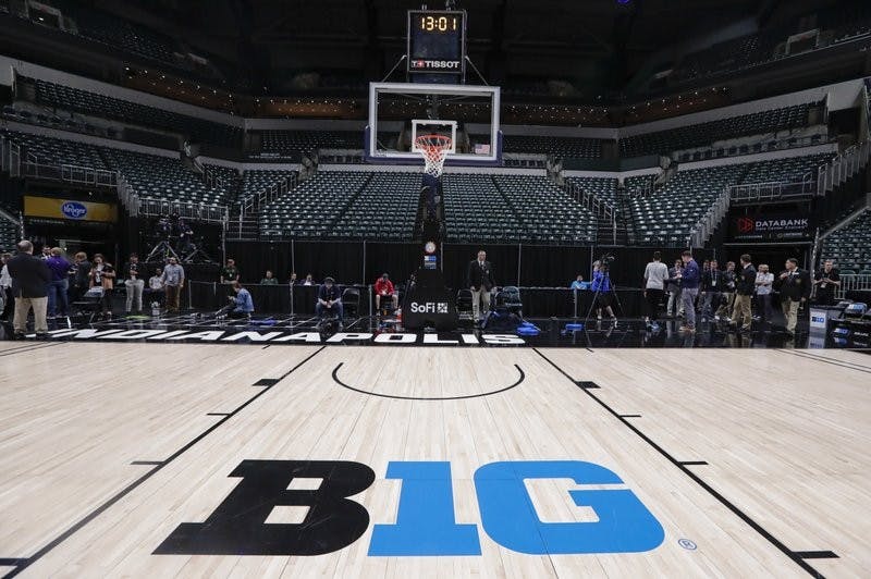The seating area at Bankers Life Fieldhouse is empty as media and staff mill about, Thursday, March 12, 2020, in Indianapolis, after the Big Ten Conference announced that remainder of the men's NCAA college basketball games tournament was cancelled. (AP Photo/Michael Conroy)