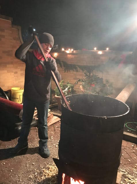 Ashton Pauley, 12, stirs kettle corn in a big pot at the Minnetrista Enchanted Luminaria Walk on Dec. 4. Ashton was helping his great uncle and grandpa out at the event to raise money&nbsp;to buy children with disabilities tricycles. DN PHOTO MICHELLE KAUFMAN