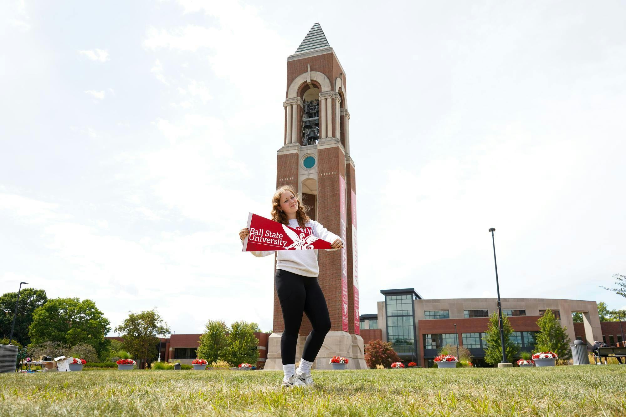 Charlotte Jons poses for a photo with a Ball State pennant flag Aug. 26 at the Shafer Tower. Jons stated that school spirit has fallen out of fashion. Isabella Kemper, DN