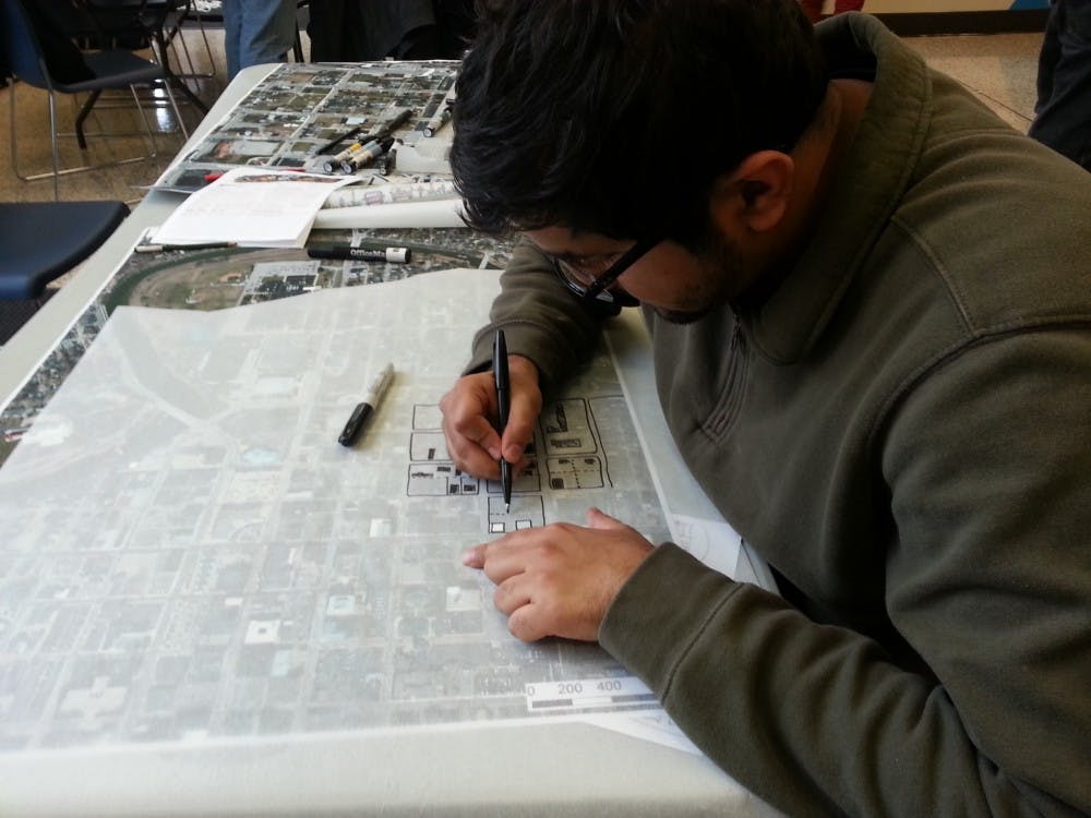 Abdulla Difalla, an urban planning graduate student, outlines structures for his group's Muncie Maker's District proposal. His group is one of four. DN PHOTO ARIC CHOKEY