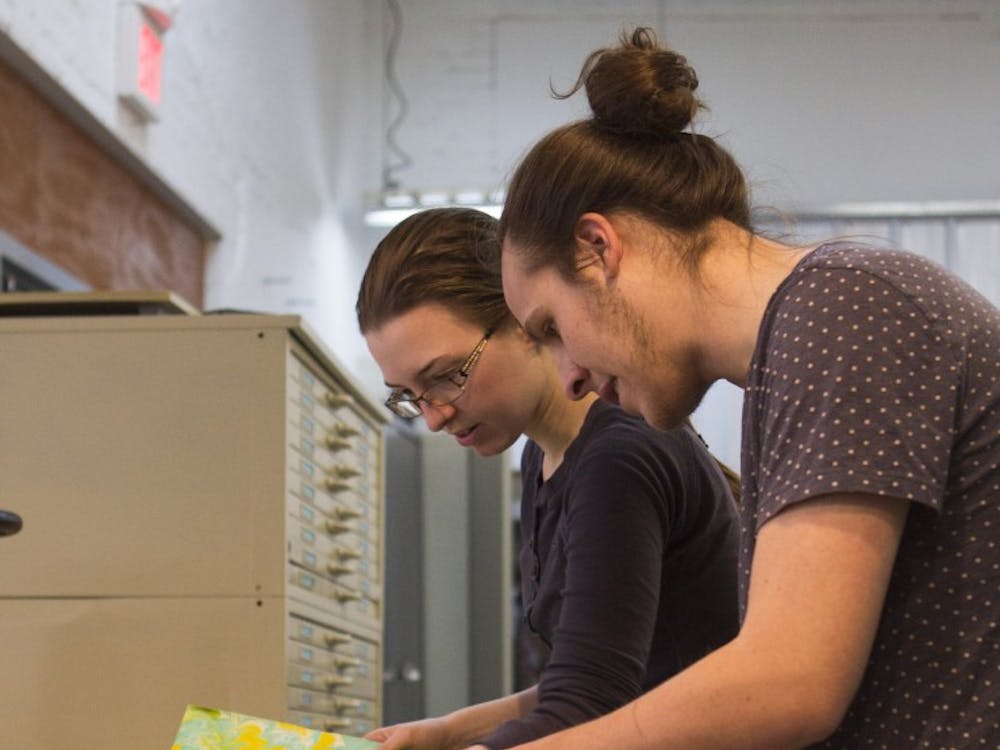 Graduate student J Collings and junior drawing major Kaitlyn Sims look through paper to choose for NAME'S book cover at the Book Arts Collaborative in downtown Muncie.  Emma Rogers // DN